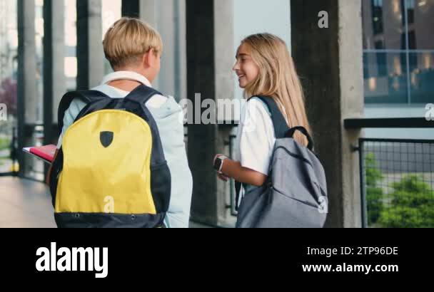 Two junior schoolchildren boy and girl walking school together to study ...