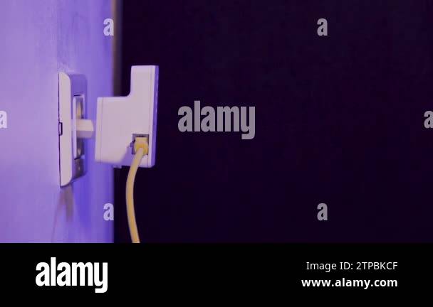 Man unplugs ethernet cable from WiFi extender device which is in