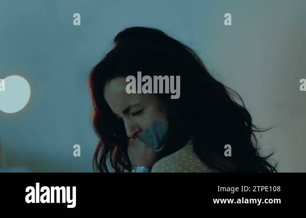 Woman hostage sitting in the basement and tied with a rope. Tape on ...