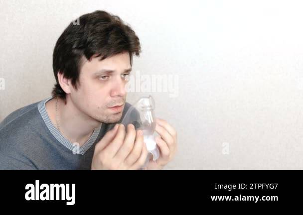 Use nebulizer and inhaler for the treatment. Young man inhaling through ...