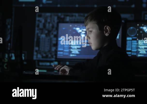 Cute teen boy programmer working at a computer in the data center ...