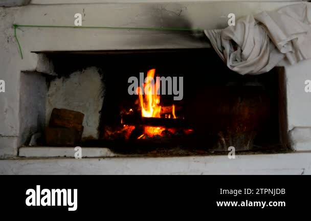 Fire is burning in a rustic wood stove. Flame heats the rural farmhouse ...