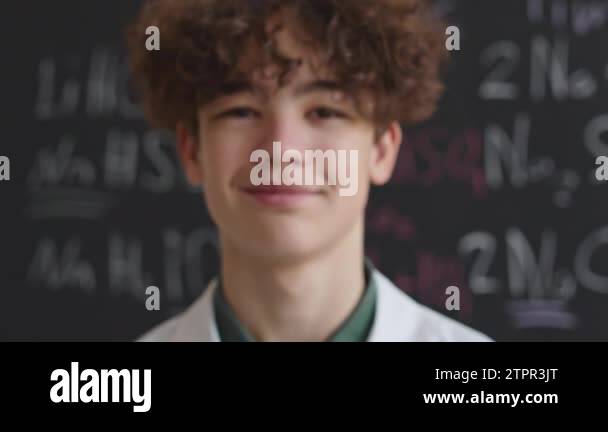 Zoom in portrait of curly haired Biracial school boy smiling at camera ...