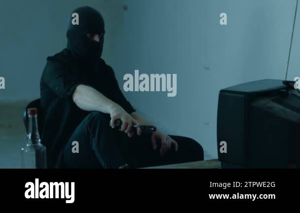 Man holding a gun and watching TV while sitting in front of the female ...