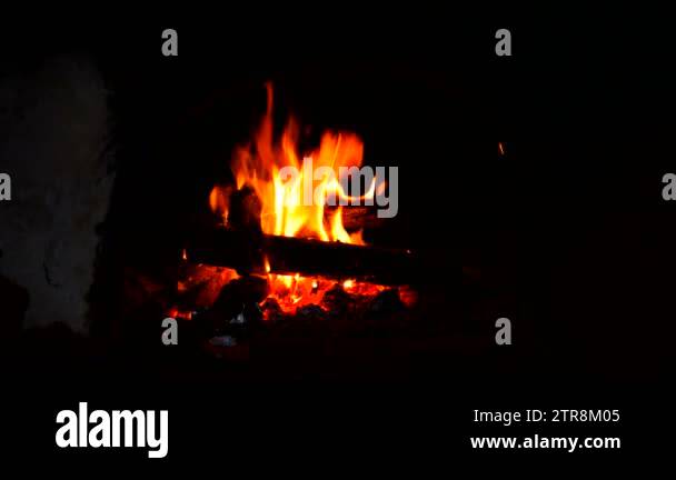 Fire is burning in a rustic wood stove. Flame heats the rural farmhouse ...