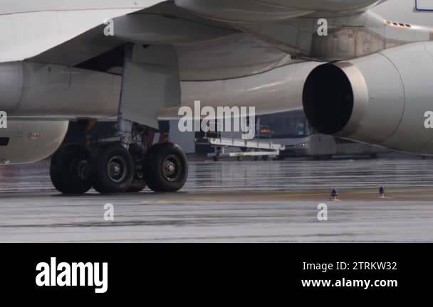 Landing gear and engine of jetliner taxiing on wet airport ramp ...