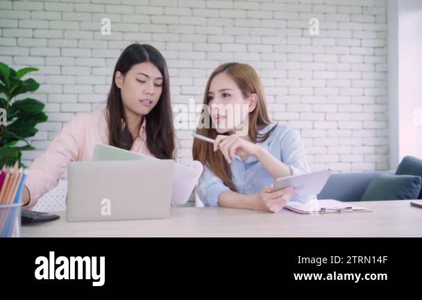 Two young Asian women working together in an office at their small ...