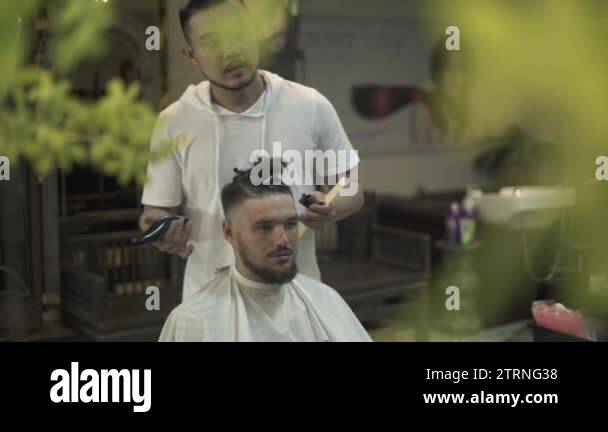 Male haircut with electric razor in barber shop. Hairdresser using hair