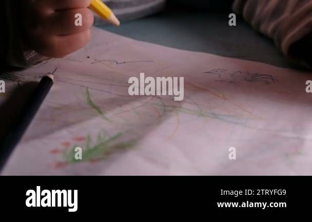 Little child draws on a sheet of paper with pencils and felt-tip pens ...