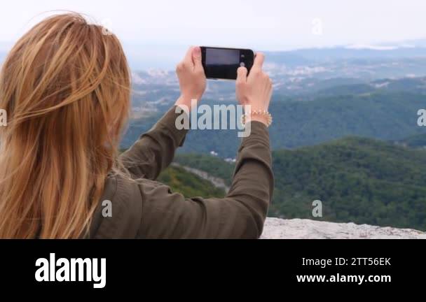 Young woman at the top of the mountain taking a selfie in slow-motion ...