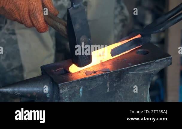 Making the knife out of metal at the forge. Close up blacksmith's hands ...