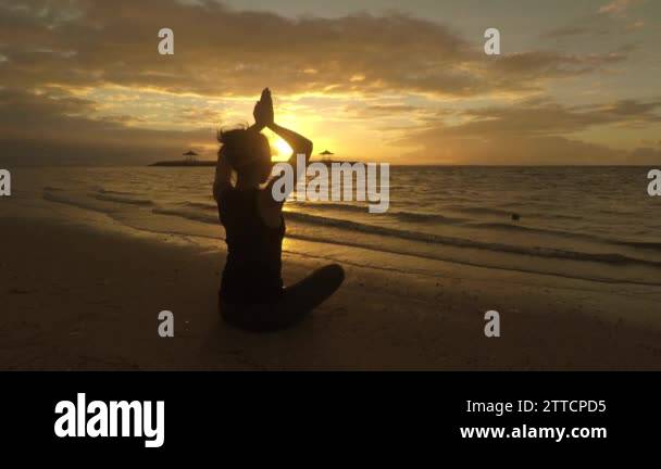 silhouette of a woman practicing yoga on the Bali beach in the early