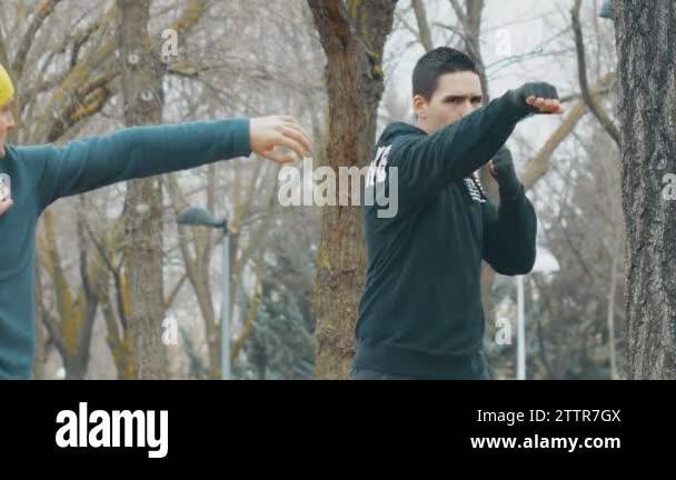 Boxing workout with trainer outdoors. Young caucasian man in black ...