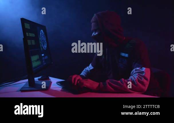 Man hacking computer sitting in a dark room. Black smoke background ...