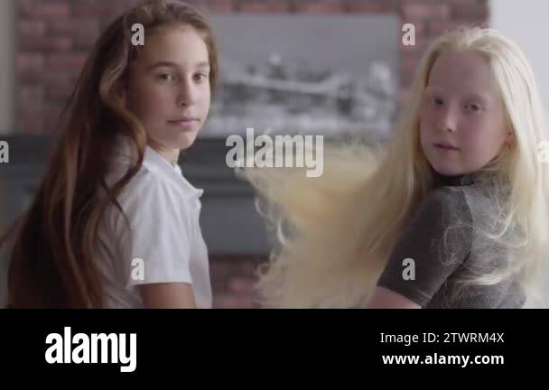 Two cute girls with long beautiful hair sitting near each other in the ...