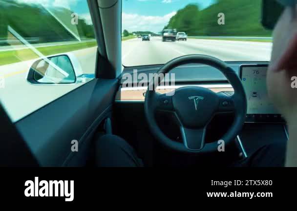 Person driving a new Tesla Model 3 in autopilot. The model 3 is set to ...