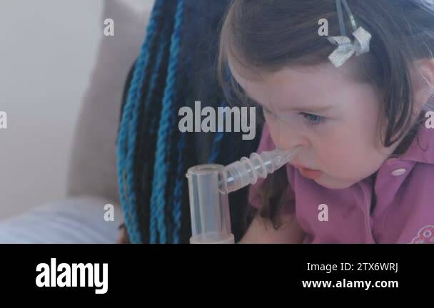 Little cute girl inhaling through inhaler mask with her mom. Use ...