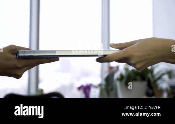 Passing file folder from hands to hands on fuzzy, office window ...