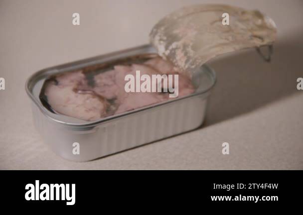 Open can with cod liver oil. From above the fork falls and punctures a ...