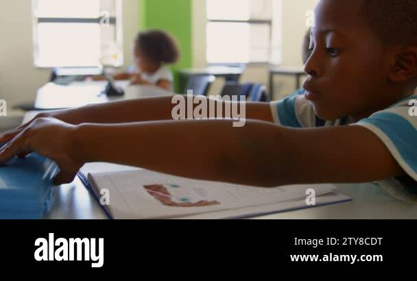 Side view of cute African American schoolboy studying while sitting ...