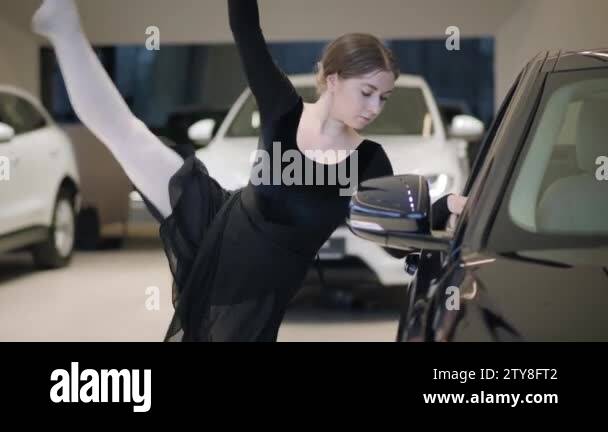 Charming Caucasian ballet dancer bending back next to black car. Pretty ...