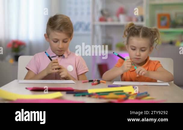 Schoolboy showing drawing to sister, childhood friendship, siblings ...