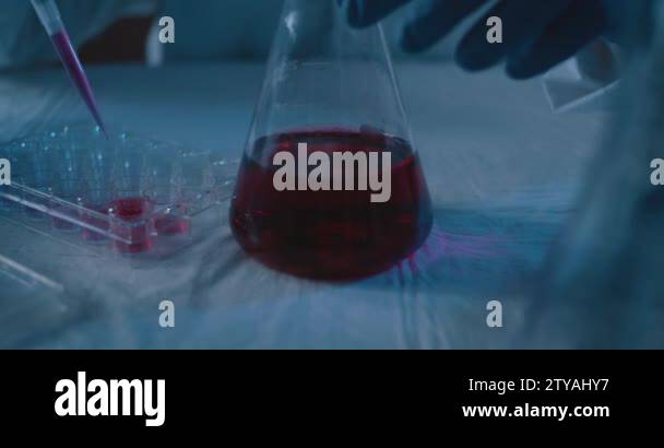 Scientist placing a red liquid sample with micro pipette into a test ...