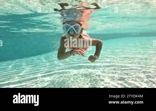 Little girl wearing snorkeling mask swimming underwater in the pool ...