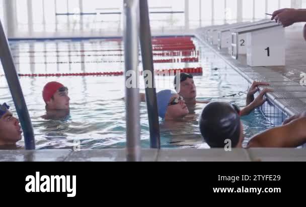 Pool Crounching Side view of Caucasian male coach and male swimmers at swimming pool ...