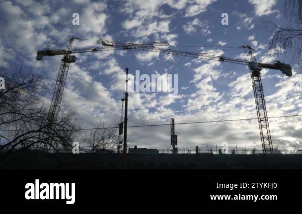 Two tower cranes on the construction site against the Sunny sky with ...