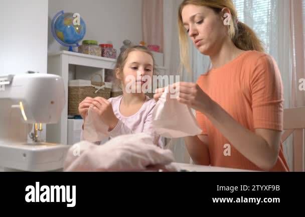 Mom teaching her little daughter to sew using needle and thread Stock ...