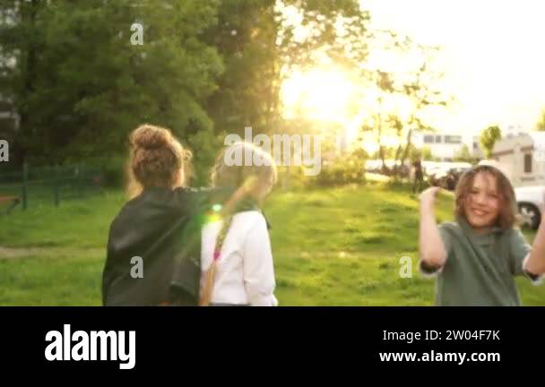 Three children, two girls and a boy go into the distance in the park ...