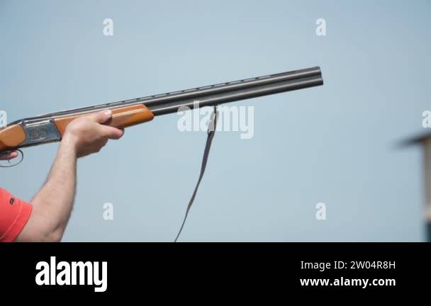 Sportive man shooting from over and under rifle aiming clay targets in ...