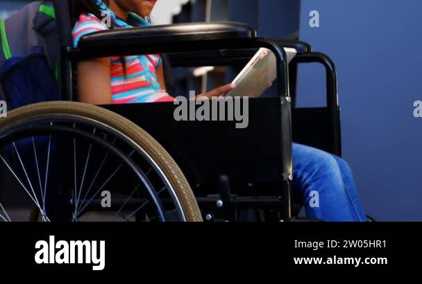Side view of disabled African American schoolgirl reading a book in ...