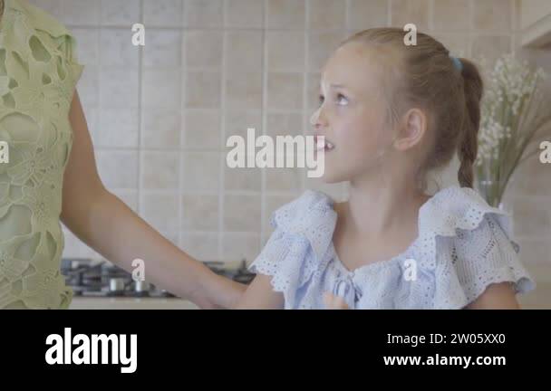 Beautiful young mother and little cute daughter cook in the kitchen ...