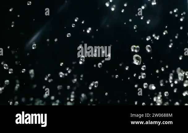 Water droplets rise in the air against Black Background. Slow motion ...