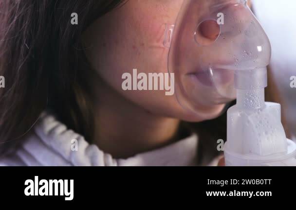 Use nebulizer and inhaler for the treatment. Young woman inhaling ...