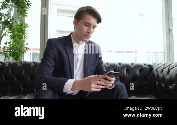 Male millennial professional holding modern smartphone texting message ...