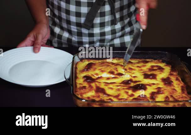 Greek moussaka dish recipe preparation. Hand serving from a transparent