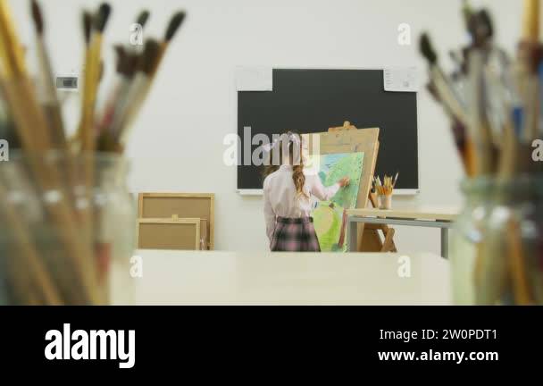 little girl paints a picture and looks at the camera. Happy little girl ...