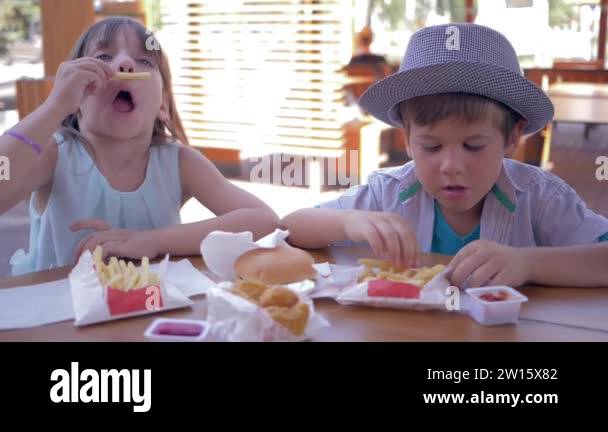 game with eat, cheerful little boy and girl play with junk meal and ...
