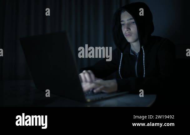 Hacker's hacking into the computer network. A young guy in a dark room ...