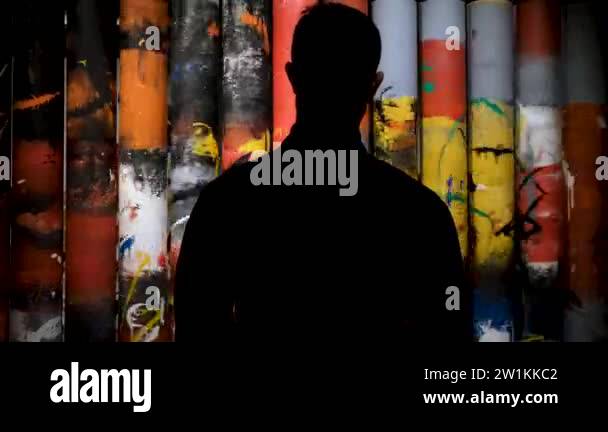 Rear view of a man silhouette standing in front of rotating columns ...