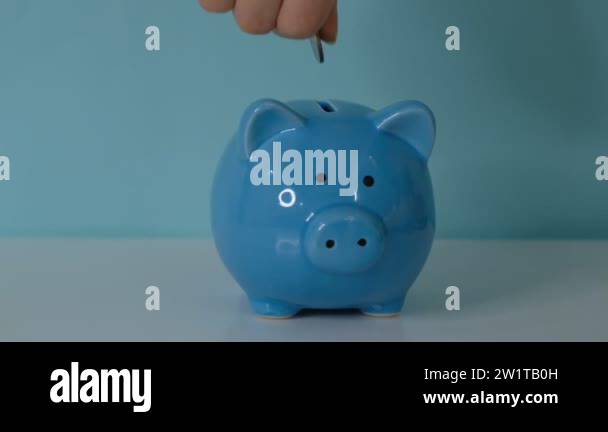 piggy bank business concept. A hand is putting a coin in a piggy bank ...
