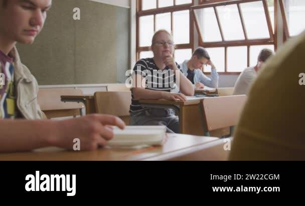 Front view of a teenage Caucasian girl in a school classroom sitting a ...