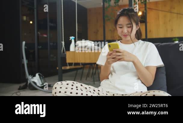 Happy cheerful young beautiful asian woman resting on the sofa after ...