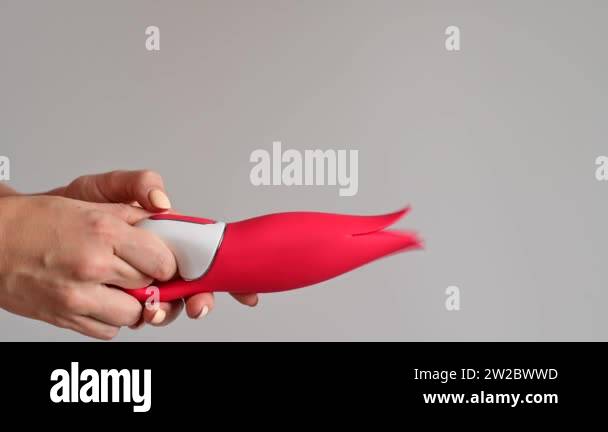 A woman holds a clitoral vibrator in the form of a red tulip. Sex toy with stylish modern design A woman holds a clitoral vibrator in the form of a red tulip. Sex toy with stylish modern design
