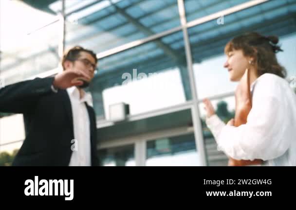 Smartly dressed young man and woman giving high five in a business ...