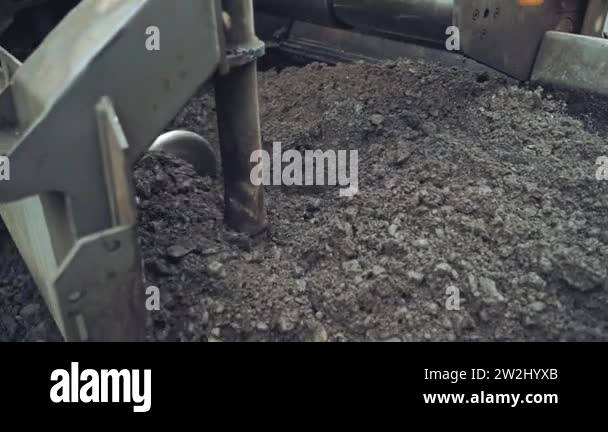 Asphalt unloaded from wheelbarrow. Paver at asphalt pavement works for ...