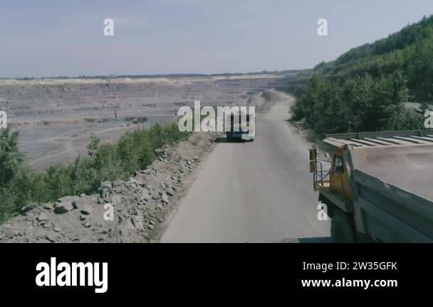 Mining dump trucks in large granite open pit mine. Loaded truck rides ...